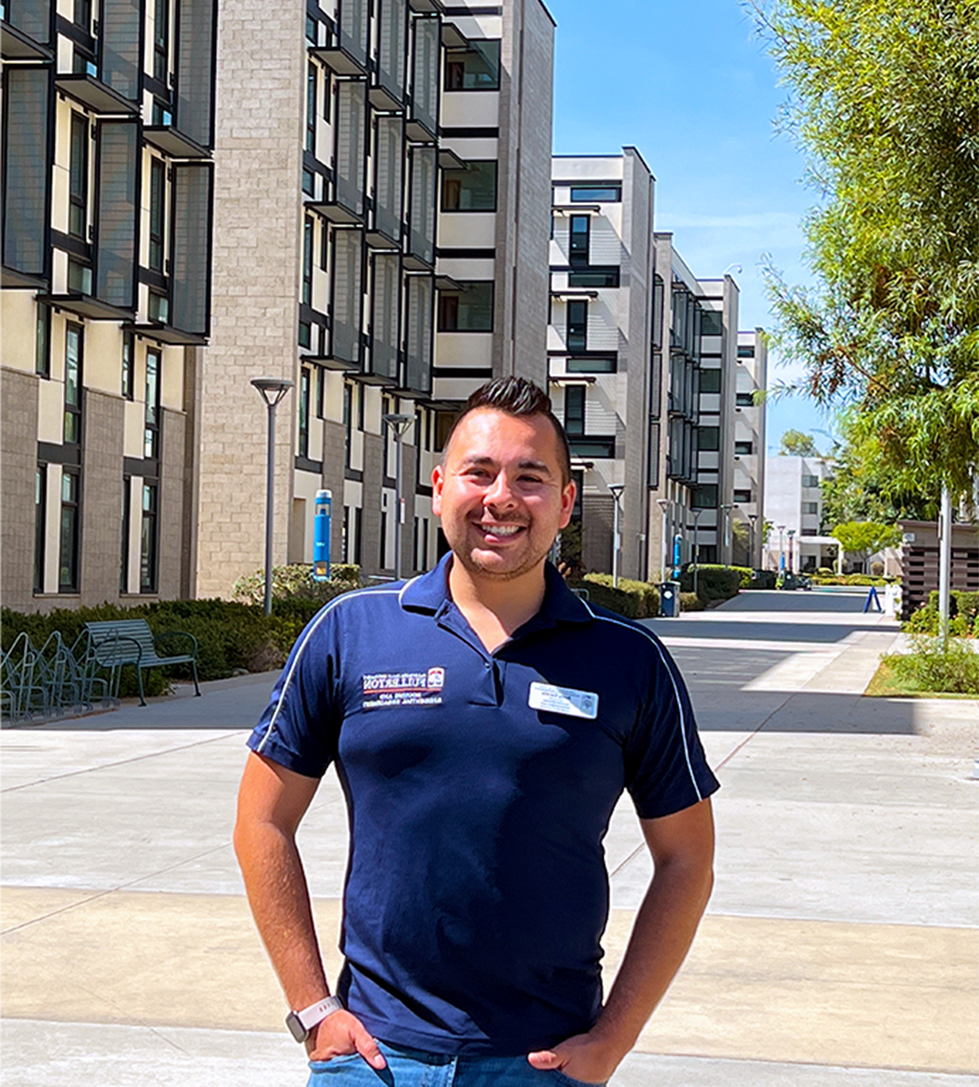 Person standing in navy blue housing and residentail engagement polo and white nametag